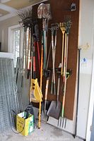 Wide shot of pegboard with long-handled rakes, shovels, pruners and fork
