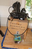 Overview of various electric fountain pumps stacked on a box labeled 'Fountain Accessories & Various Pumps'