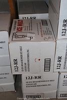 Stacked cardboard boxes labeled '12J-RR' containing 12 lb Road Runner Ice Melt jugs, four boxes visible