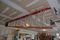 Photo showing the full 10 ft Werner ladder hanging in a garage, displaying its orange fiberglass sides and metal rungs.