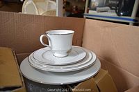 Stack of Sango china pieces that includes cup, saucer, salad plate, and dinner plate with platinum band edged rim.