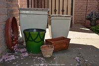 Five patio planters arranged on stone surface outdoors showing variety in shapes and colors including cream glazed, green glazed, and terracotta styles.