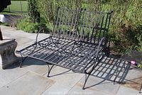 Full view of double metal patio lounger on stone patio, showing lattice slatted seat and two adjustable backrests.