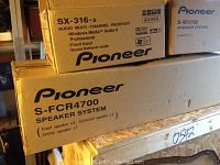 Boxes of Pioneer SX-316-S multi-channel receiver and S-FCR4700 speaker system stacked, showing model information and features.