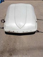 Top view of the cargo carrier showing white shell with mounting straps on side and some wear marks.