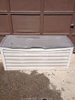 Front view of gray plastic outdoor storage container with horizontal panel design and hinged lid.