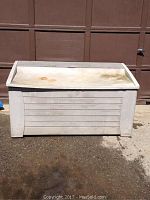 Front view of large light grey plastic outdoor storage container with lid showing discoloration and rust spots.