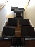 Photo showing 8 laptops arranged on stair steps and a plastic cart, various brands and sizes visible