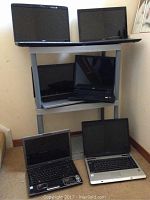 Six laptops arranged on shelves and floor showing front and keyboard sides.