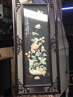 Full view of the wooden framed floral relief art piece showing overall shape, carved corners, floral carved elements and written script.