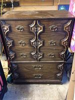 Full front view of the dark wood wooden dresser with carved detailing and metal handles.