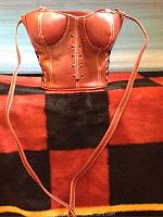 Photo of the front of the red leather corset-style purse showing bustier design, metal studs, stitching, and long strap.