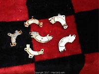 Six curved neodymium magnets mounted on metal backing plates arranged on a red and black checkered surface.