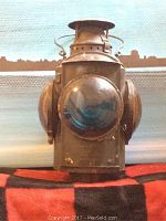 Front view of lantern showing convex blue-tinted lens and steel housing