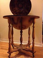 Full view of globe bar on wooden stand with four turned legs and caster wheels