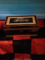 Closed vintage money lock box showing the top handle and decorative exterior.