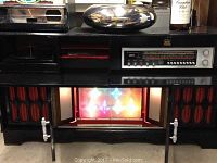 Front view showing control panel, illuminated decorative colored lights, and speaker grills with red fabric.