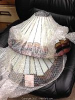 Photo of two stained glass lamp shades wrapped in bubble wrap placed on a black surface.