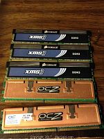 Top side view of 3 Corsair XMS3 DDR3 RAM modules and 2 OCZ DDR3 RAM modules stacked, showing model, brand, and heat spreaders.