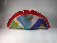 Full view of large curved art glass bowl with folded ruffled edges and vibrant multicolor pattern.