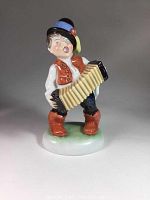 Front view of the Herend porcelain figurine of a boy playing an accordion, showing detailed painting and colors.