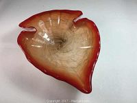 Top-down angled view of the Murano arrowhead shaped glass bowl showing fluted red rim and gold flecks inside.