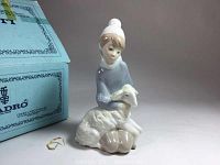 Front and side view of Lladro figurine girl with sheep next to original blue box