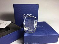 Topdown view of the crystal paperweight outside original box, showing its clear faceted cut and horse shapes inside