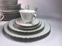 Stacked plates and cups showing swirl pattern with silver rims and size variety
