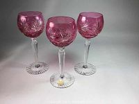 Three pink and clear crystal wine glasses with strawberry cut decoration seen upright from front