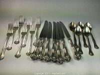 Full view of 7 dinner forks, 7 knives, and 5 teaspoons arranged in a row