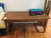 Wooden coffee table showing overall structure, wood finish, and drawer front.