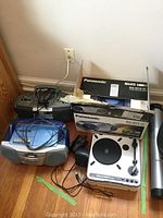 Panasonic RX-D13 CD player in box along with two boomboxes and the portable USB turntable on wooden floor.