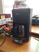 Krups drip coffee maker black with glass pot, digital display on front, seen on wooden table