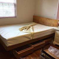Full view of maple platform bed frame with headboard, mattress in place, drawers pulled out