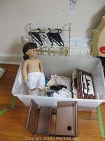 Plastic tote with doll, underwear, disassembled wood desk parts and clothes tote