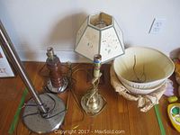 Four lamps shown on wooden floor including tall floor lamp, two smaller lamps with floral lampshades, and a basket. Visible rust and soiling on lamps.