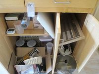 Photo of open kitchen cabinet with various baking and cooking items stored inside including silicone baking mat, mixing bowl, and boxes of items.