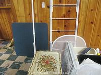 Wide view of laundry racks, card table and floral tray on wire shelving side table, small plastic gate, and trash cans
