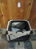 Beige canvas dog crate top view, showing zippered mesh opening and handles inside the crate.