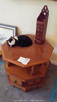 Photo of the octagon pecan side table with faux cat and small storage rack on top, showing color, condition, and included items.