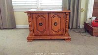 Pecan-colored wood square side table closed showing front doors and decorative handles and spindle details.