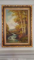 Frontal photo of the framed oil painting showing the river landscape with birch trees and autumn colors.