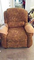 Front view of the Havertys upholstered recliner showing the paisley pattern fabric and light brown armrest covers.