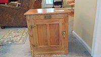 Front and side view of oak wood ice chest style side table showing brass hinges and handle.