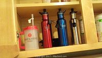 Shelves with drink containers including plastic Saint Josephs Hospital branded mug and metal water bottles in red, blue and silver