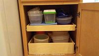 Cabinet shelves with stacked plastic storage containers and bowls of various colors and sizes