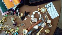 Mixed gold-tone and beaded watches, assorted rings and earrings on table with cloth pouches
