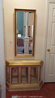 Curio cabinet below matching tall framed mirror, showing overall front view of both pieces.