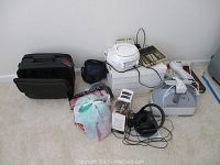 Photo of lot showing black Targus laptop case, Kodak DX3700 camera with dock, miscellaneous small electronics and personal care items arranged on floor against wall.